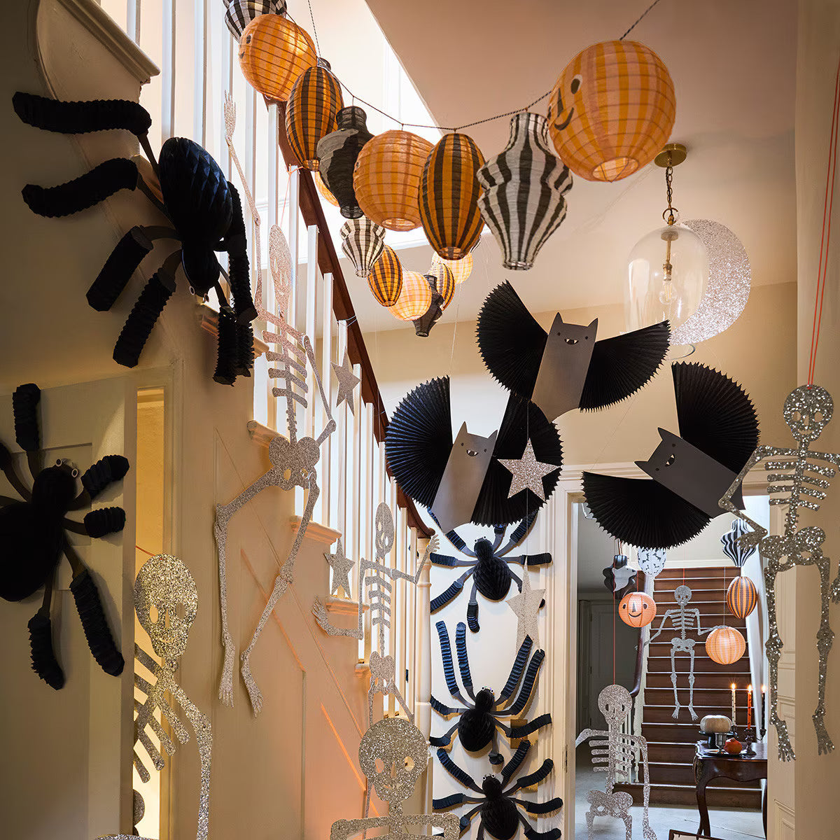 Halloween display in the Leigh-on-Sea shop, with black paper spiders, orange and black honeycomb lanterns strung overhead and a skeleton beside the shelves